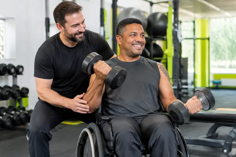 Aluno cadeirante treinando braços com o personal